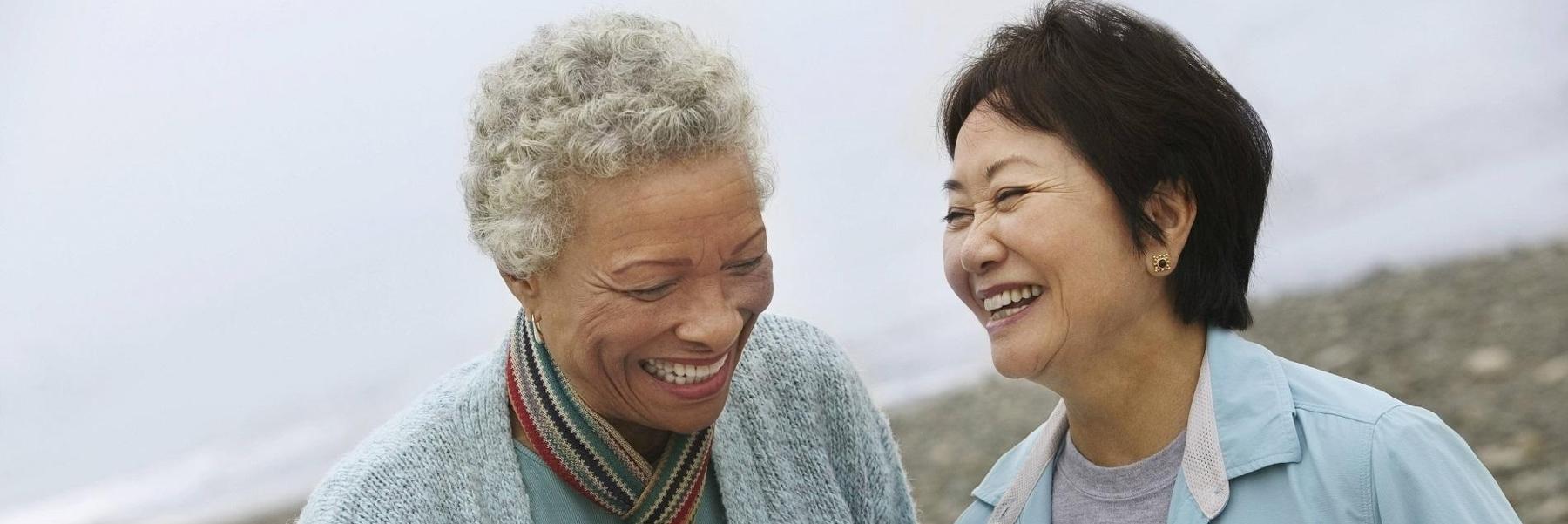 Two elderly woman smiling on the beach 