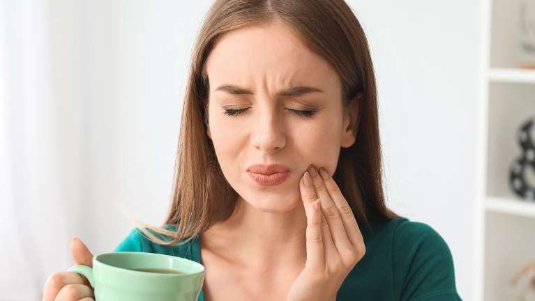 Woman experiencing tooth sensitivity due to hot coffee in Phoenix AZ