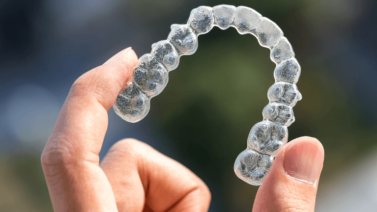 Hand holding clear dental aligner in Phoenix