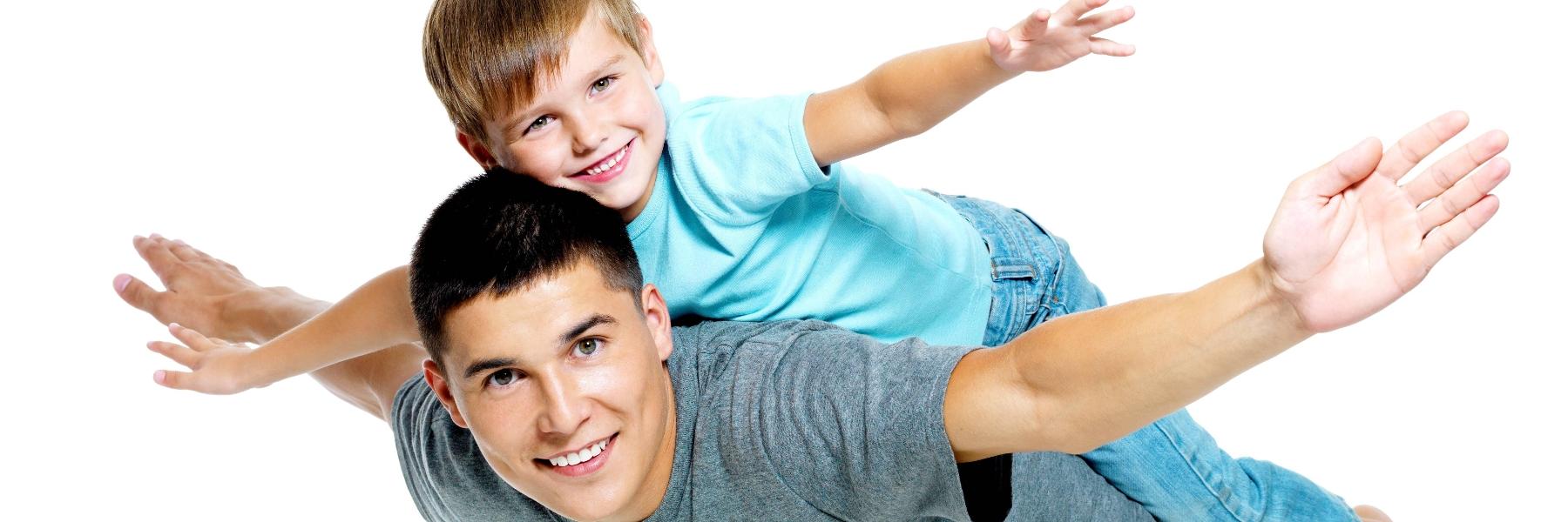 Dad giving his son a piggy back ride and smiling 