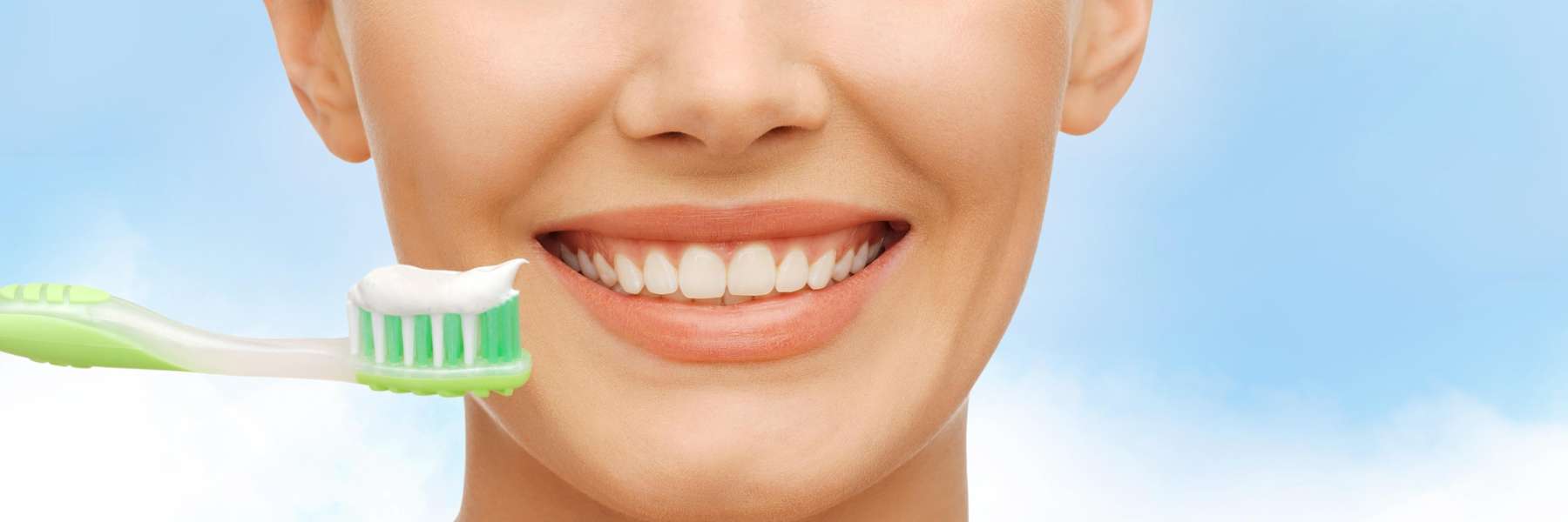 close up of woman smiling while using a toothbrush with tooth paste
